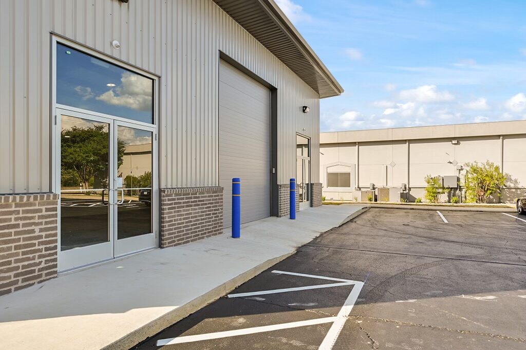 Angled view of the office and warehouse showing the soffited roof overhang, brick wainscot and glass entry doors