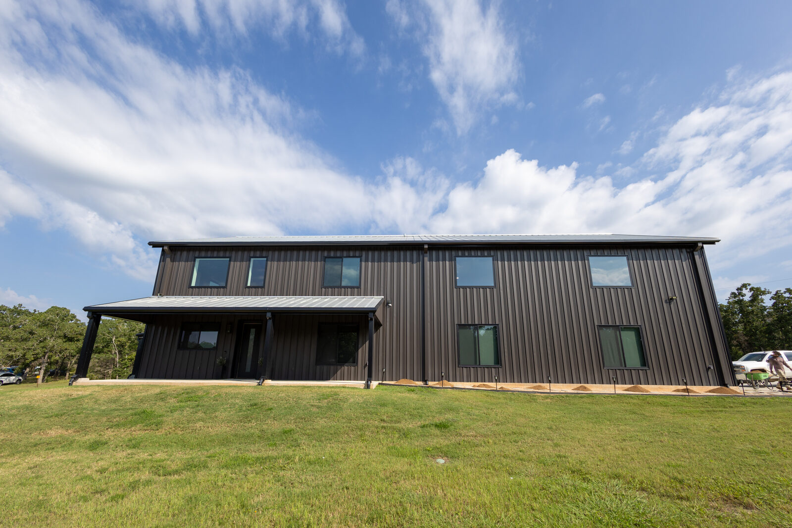 Black 50 by 84 barndominium in College Station, Texas with a covered entry porch and two storeys of windows