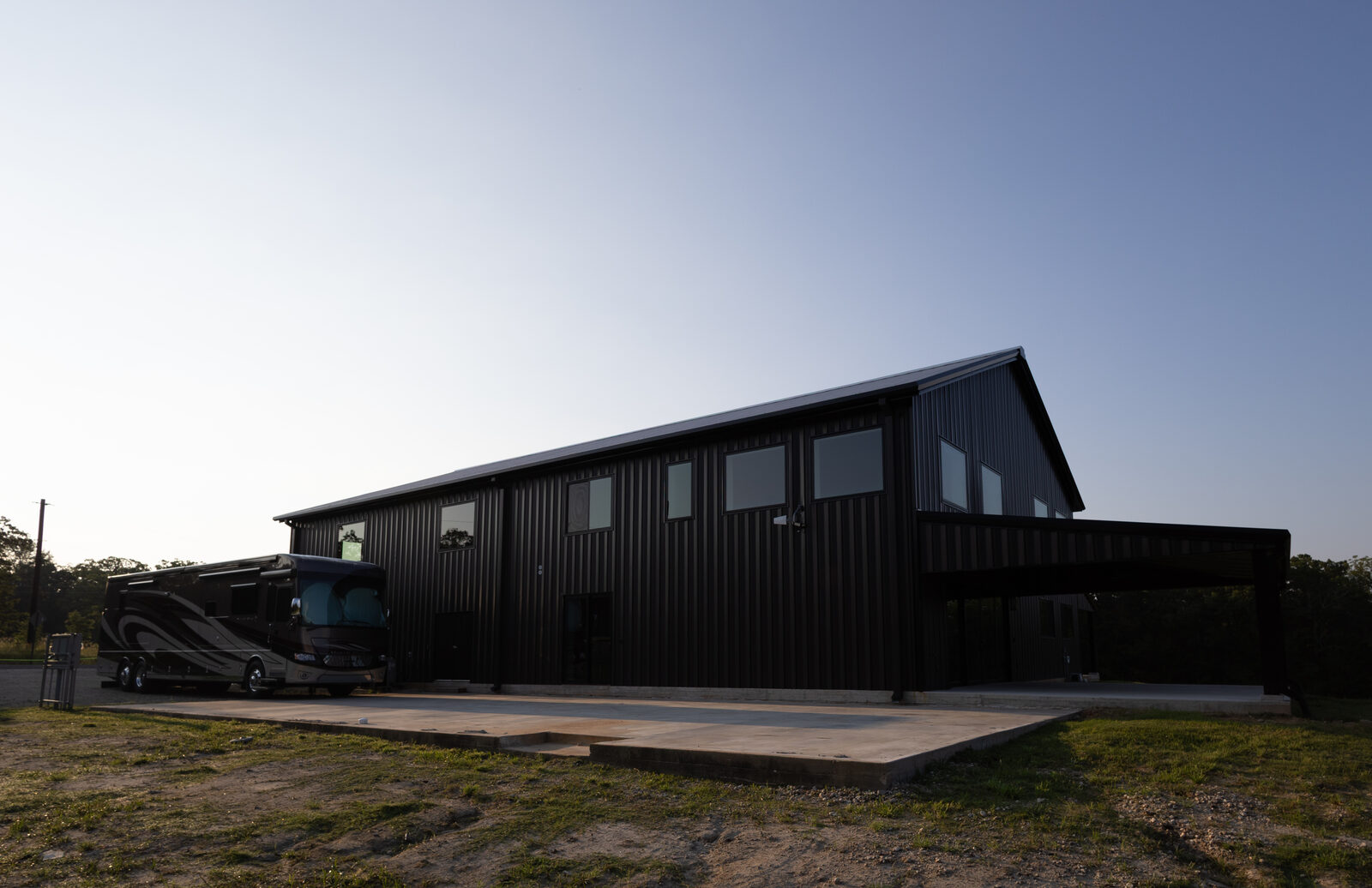 The barndominium at sunset with a motorhome parked alongside the shop end