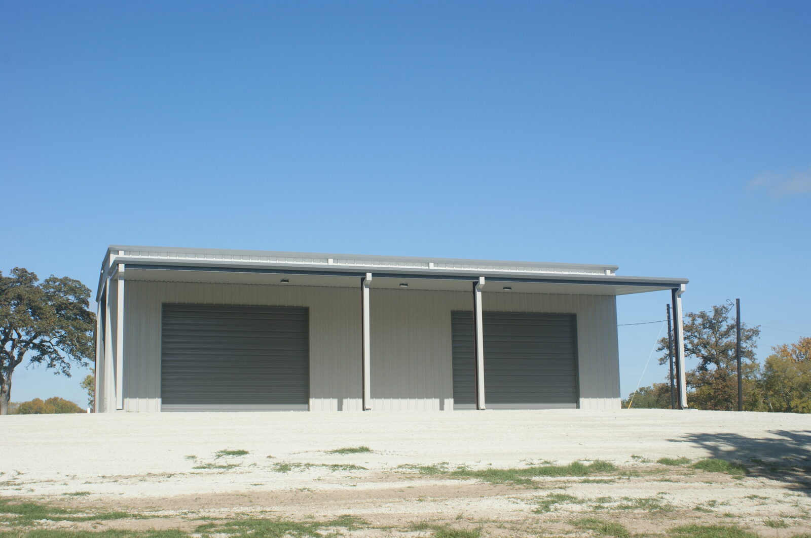 Straight-on view of the sidewall with two overhead doors and an open lean-to