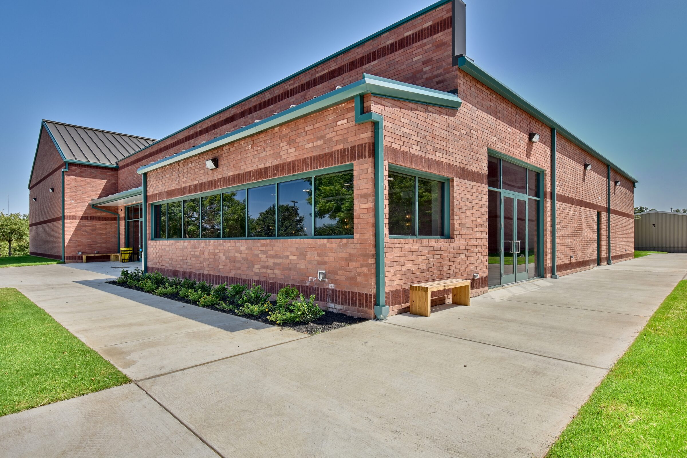 Brick and steel community building with teal trim and a long ribbon of windows, built by Rhodes Building Systems