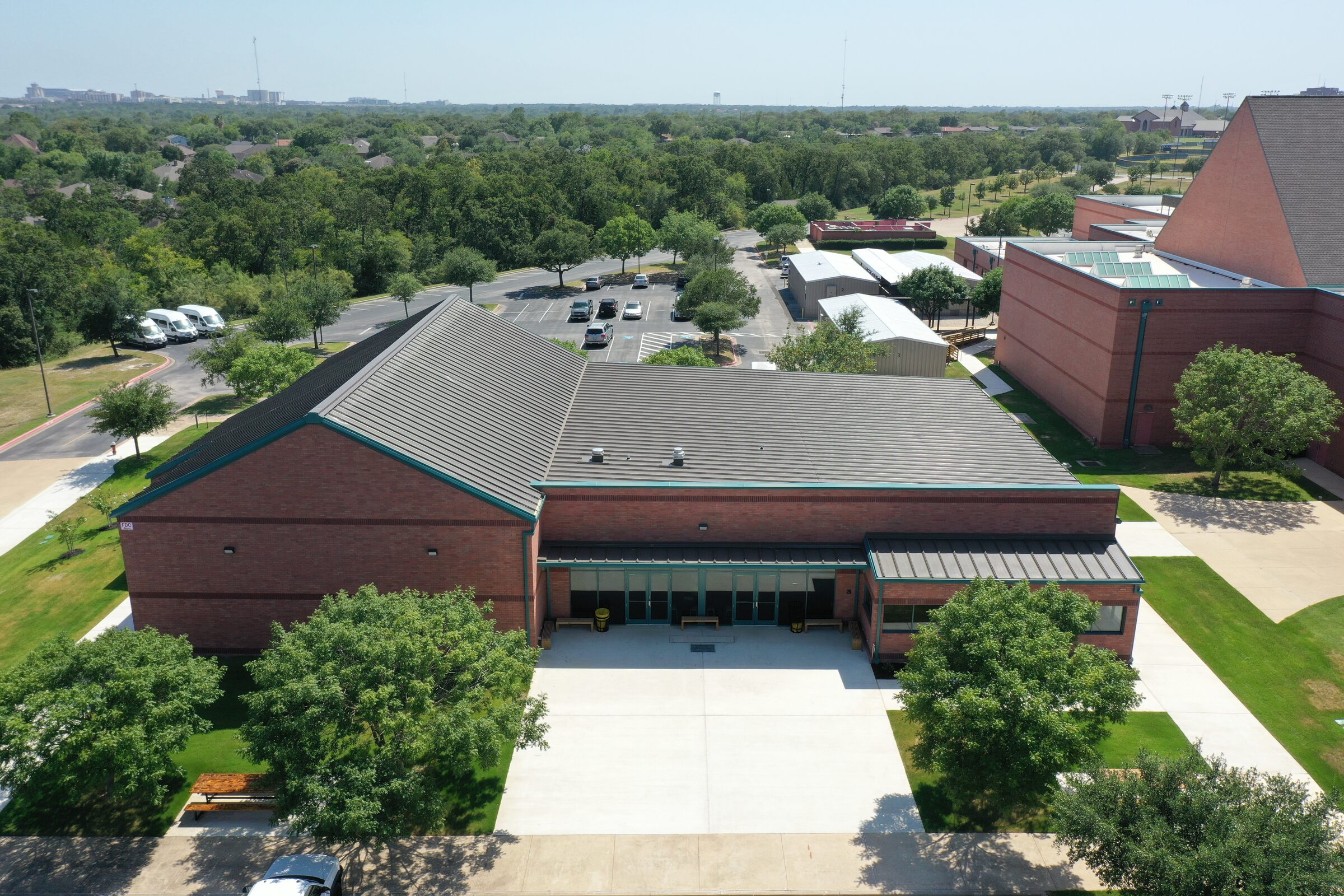 Aerial view of the completed brick building, its standing-seam roof and the covered entry plaza