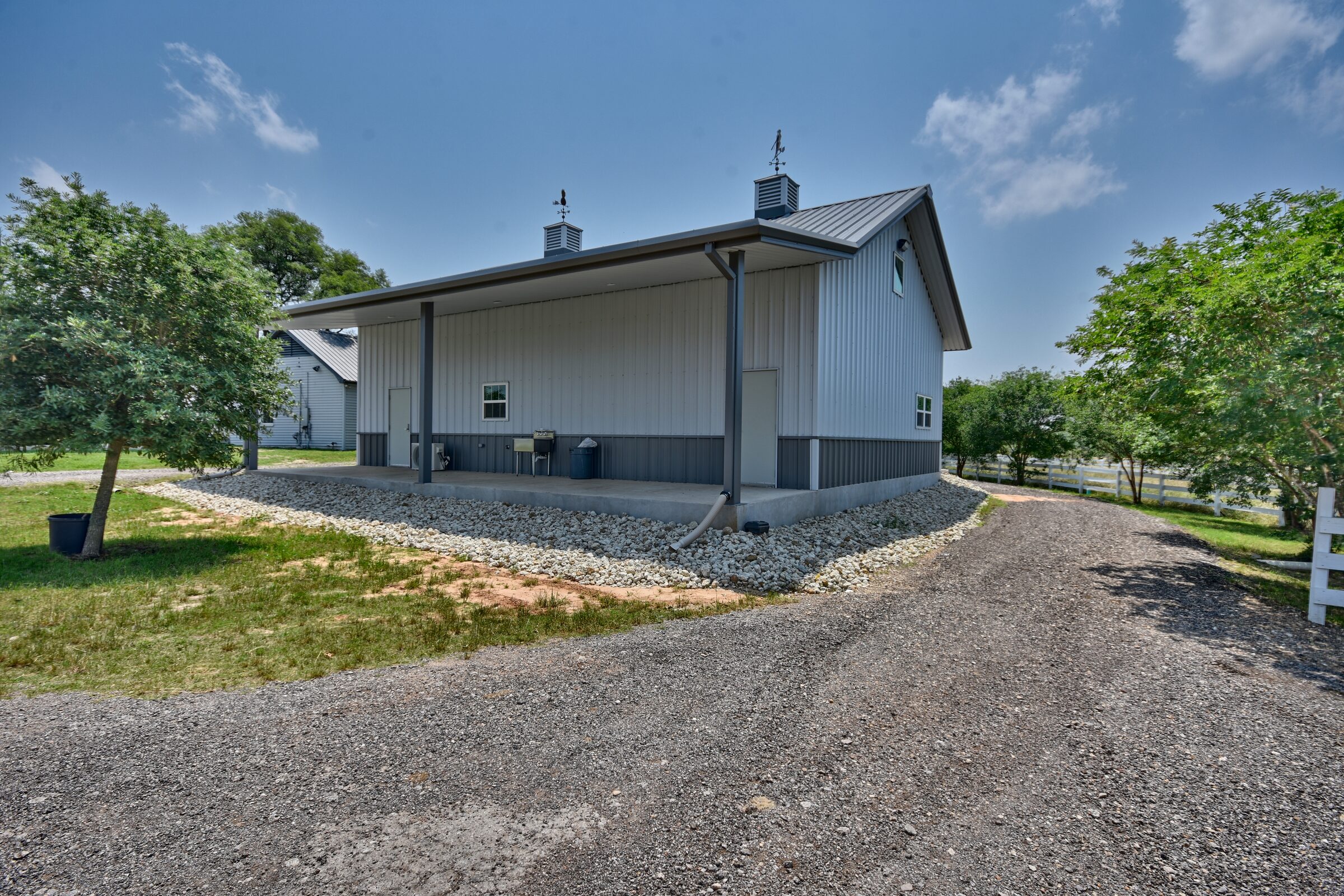 Rear three-quarter of the shop building showing the deep covered porch running the length of the wall