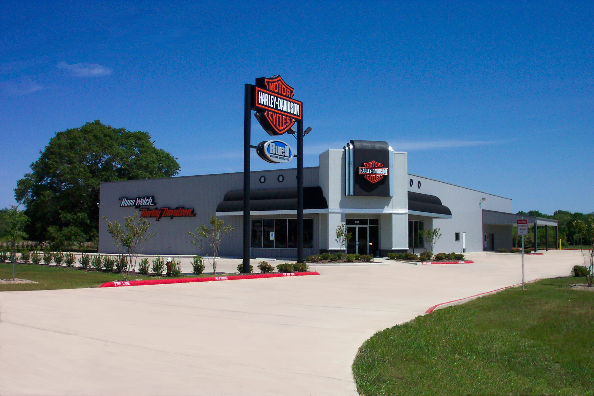 Harley-Davidson dealership built by Rhodes Building Systems, with a grey metal exterior, black awnings and a tall pylon sign