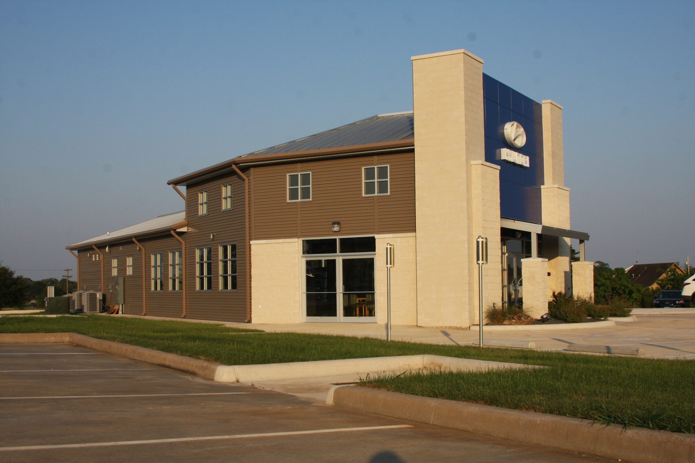 Hyundai dealership with a stone entry tower, brown lap siding and a standing-seam roof